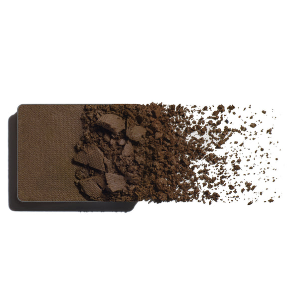 Brown eyeshadow refill with scattered powder on a white background
