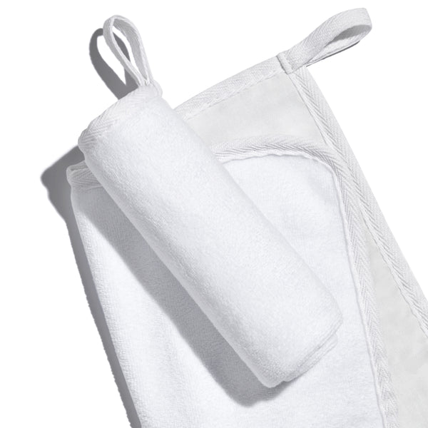 White, banded, Lisa Eldridge Luxuriously Gentle Cleansing & Exfoliating Cloth, one flat and one rolled up on top, showing different textures of the cloth faces and a loop for hanging up
