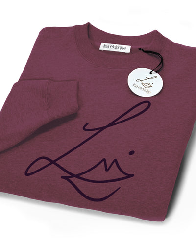 The Lisa Eldridge Studio Sweatshirt in velvet midnight folded up. The crewneck and the cuffs have a fine rib. The Lisa Eldridge logo is large on the front. There is a label that says “lisa eldridge’ sewn on the inside. Attached to the size label is a circular card tag on a black ribbon with the Lisa Eldridge logo in gold