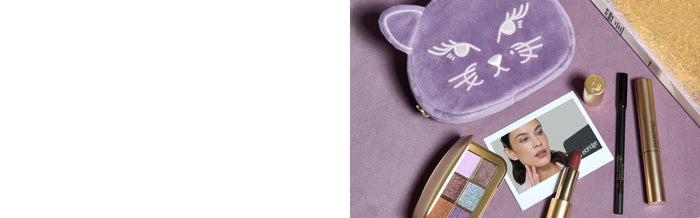 Lisa Eldridge products including Betty Eyeshadow Palette, Velvet Lipstick, Seamless Glide, Kitten Lash and Betty Kitten Pouch, on a purple surface with a book and polaroid photo of Alexa Chung wearing the eyeshadow.