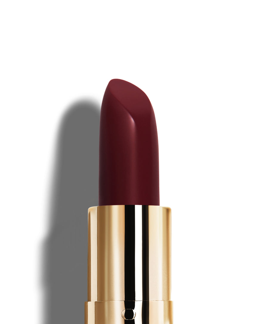Deep claret lipstick with gold casing on a white background