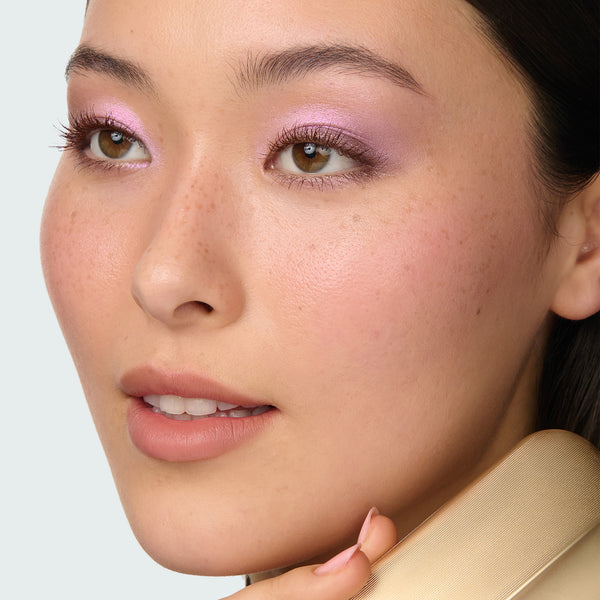 Close-up of a model with pink eyeshadow from the Betty Palette on a light gray background