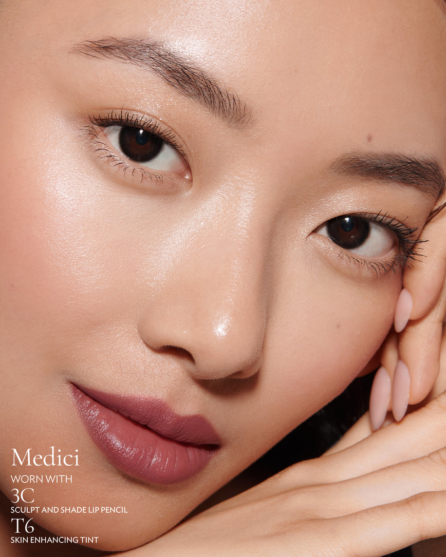 Close-up of a woman with a grey background, focusing on the lip colour - mauve berry Medici, with notes on the 3C Sculpt and Shade Pencil and T6 Skin Enhancing Tint