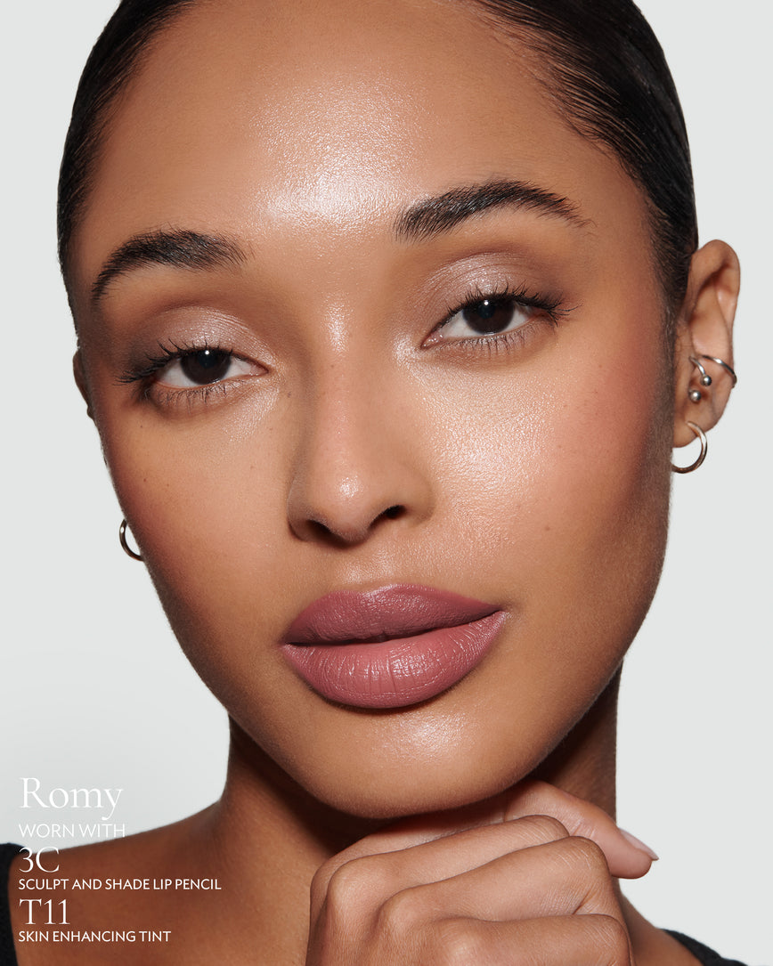 Close-up of a woman with a grey background, focusing on the lip colour - muted heather Romy, with notes on the 3C Sculpt and Shade Pencil and T11 Skin Enhancing Tint