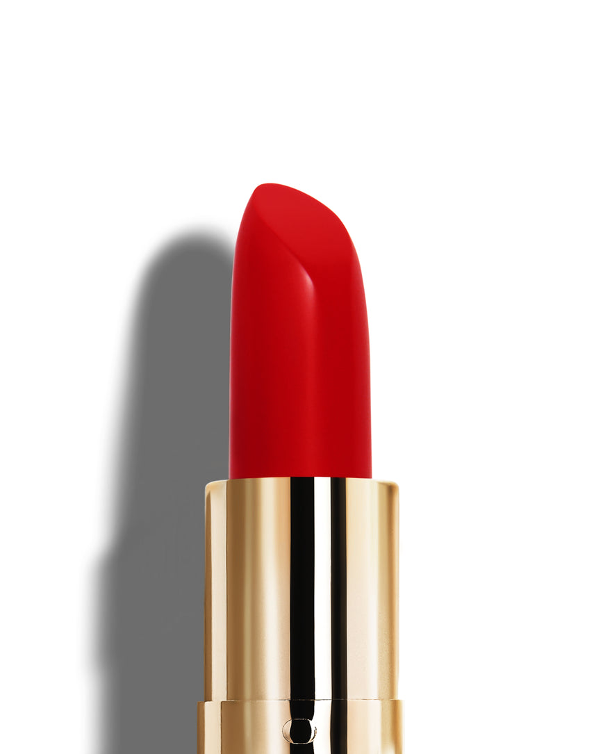 Pillar-box red lipstick with gold casing on a white background