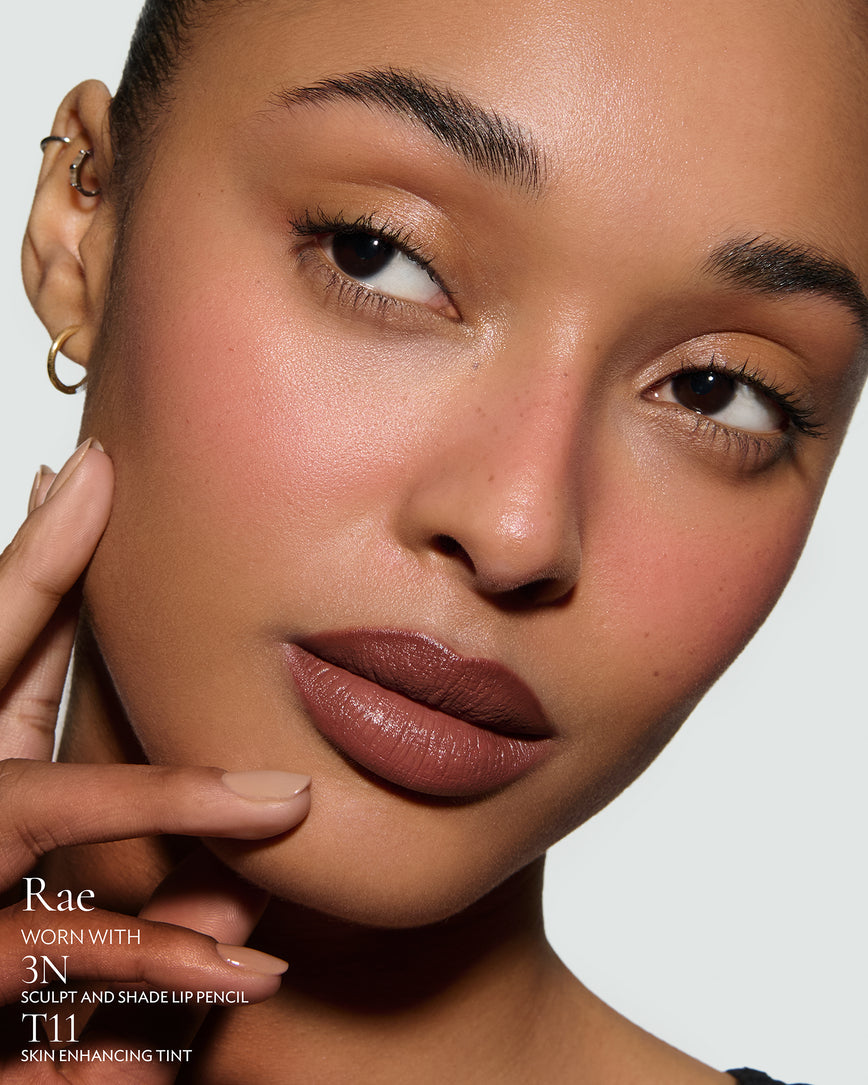 Close-up of a woman's on a neutral background. Model is wearing Rae Rouge Experience, a chocolate-red lipstick, with 3N Sculpt Pencil and T11 Tint