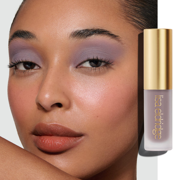Model wearing Maude Liquid Silk  Eyeshadow with the product in the foreground on a white background.