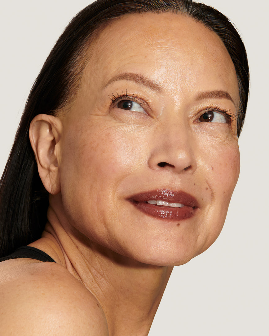 Model with a warm smile, against a neutral background, wearing Metropolis Baume Embrace