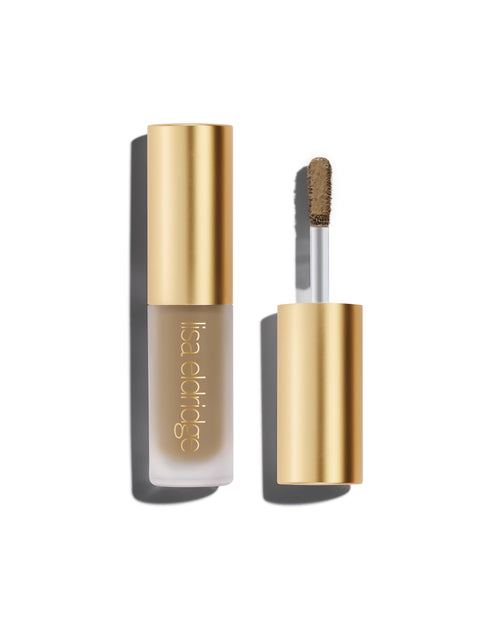 A closed bottle of Lisa Eldridge Liquid Silk Liquid Eyeshadow in shade Mimi, with a gold cap containing an applicator wand with product on it, against a white background.