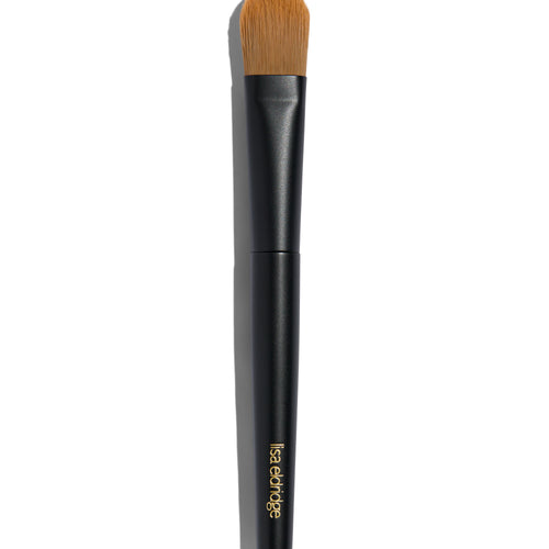 Foundation brush with a long black handle and a flat rounded brush. The handle says ‘lisa eldridge’ in gold at the bottom