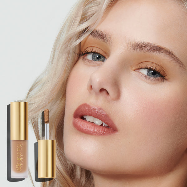 Close-up of a model's face, wearing Liquid Silk, with the product pack in the foreground on a neutral background