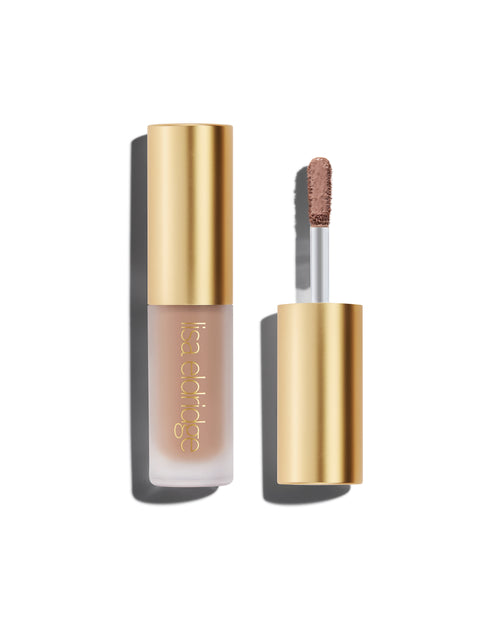 A closed bottle of Lisa Eldridge Liquid Silk Liquid Eyeshadow in shade Silvia, with a gold cap containing an applicator wand with product on it, against a white background.