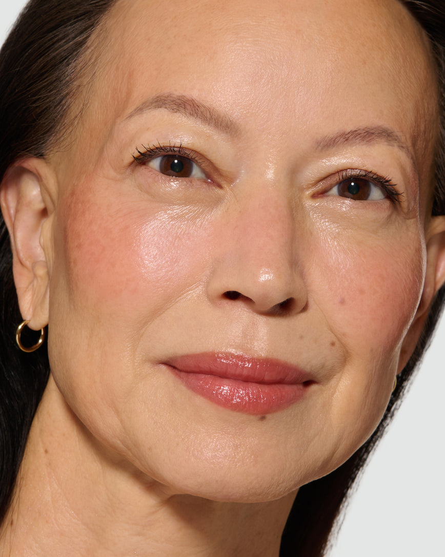 Close-up of a model's face with a neutral background, wearing Velatura Balm in shade Cinnamon Bun