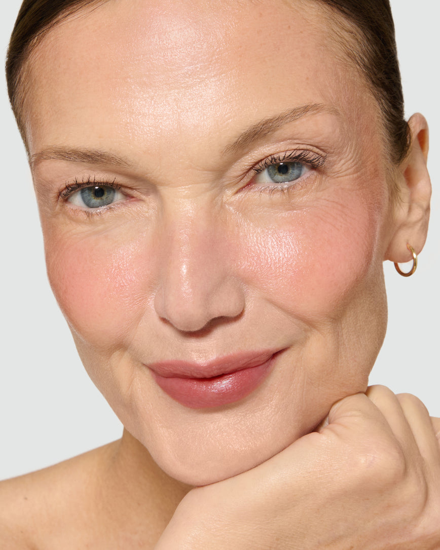 Close-up of a model's face with a neutral background, wearing Velatura Balm in shade Cinnamon Bun
