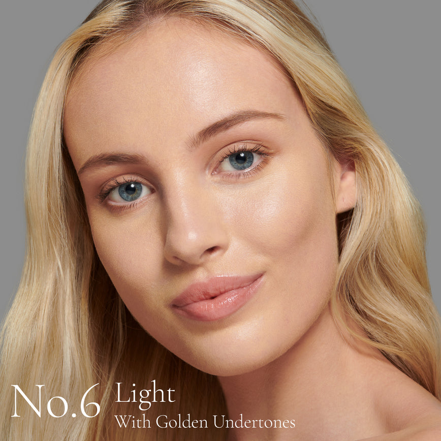 Lisa Eldridge Seamless Skin Foundation Pictured on Model. A young model with light skin and golden undertones, blue eyes and blonde straight hair. The text says ‘No.6 Light With Golden Undertones'