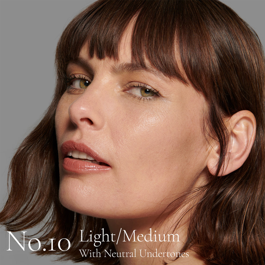 Lisa Eldridge Seamless Skin Foundation Pictured on Model. The model has light/medium skin and neutral undertones, green eyes and slightly wavy chestnut hair. The text says 'No.10 Light/Medium With Neutral Undertones’