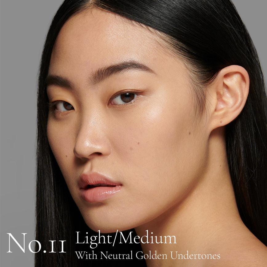 Lisa Eldridge Seamless Skin Foundation Pictured on Model. The model has light/medium skin and neutral golden undertones, brown eyes and straight black hair. The text says 'No.11 Light/Medium With Neutral Golden Undertones’