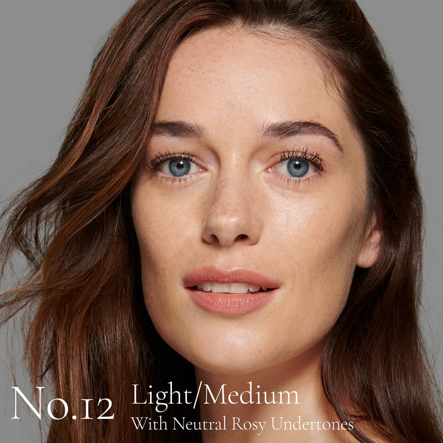 Lisa Eldridge Seamless Skin Foundation Pictured on Model. The model has light/medium skin and neutral rosy undertones, blue eyes and slightly wavy brown hair. The text says ‘No.12 Light/Medium With Neutral Rosy Undertones’