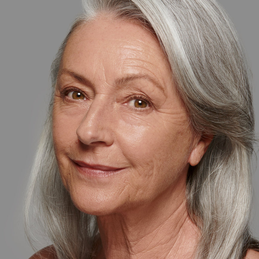 Lisa Eldridge Seamless Skin Foundation Pictured on Model. The model has light/medium skin and rosy undertones, brown eyes and straight grey hair.