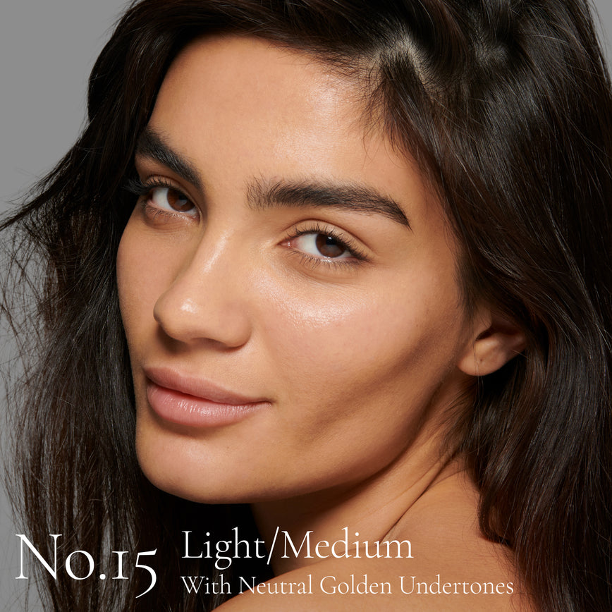 Lisa Eldridge Seamless Skin Foundation Pictured on Model. The model has light/medium skin and neutral golden undertones, brown eyes and straight black hair. The text says ‘No.15 Light/Medium With Neutral Golden Undertones’