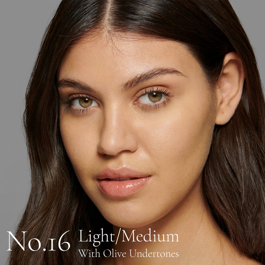 Lisa Eldridge Seamless Skin Foundation Pictured on Model. The model has light/medium skin and olive undertones, green/hazel eyes and straight dark brown hair. The text says ‘No.16 Light/Medium With Olive Undertones’