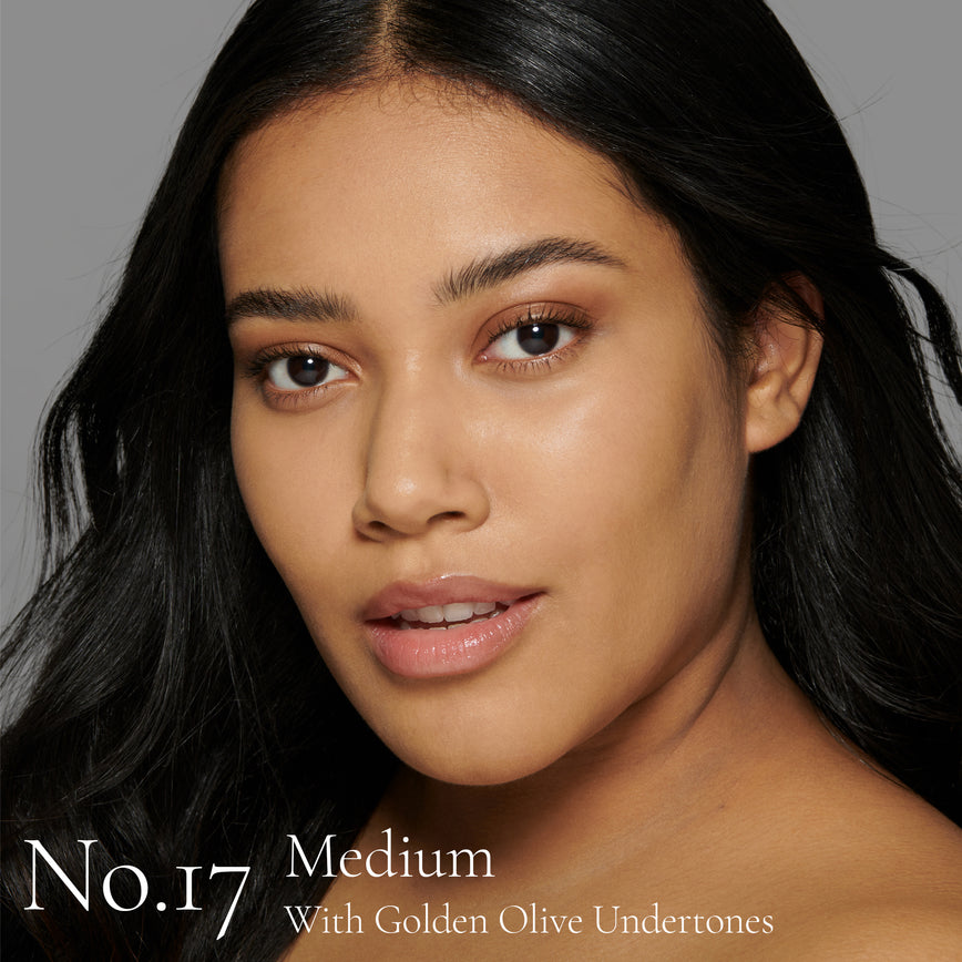 Lisa Eldridge Seamless Skin Foundation Pictured on Model. The model has medium skin and golden olive undertones, brown eyes and slightly wavy black hair. The text says ‘No.17 Medium With Golden Olive Undertones’