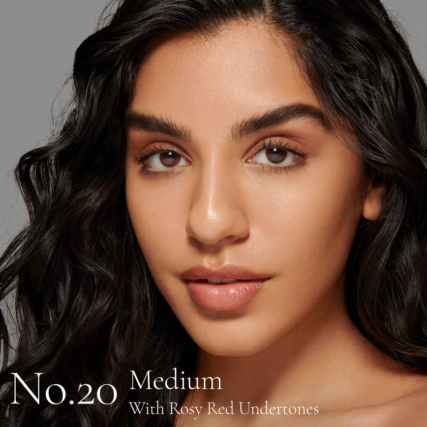 Lisa Eldridge Seamless Skin Foundation Pictured on Model. The model has medium skin and rosy red undertones, brown eyes and black wavy hair. The text says ‘No.20 Medium With Rosy Red Undertones’