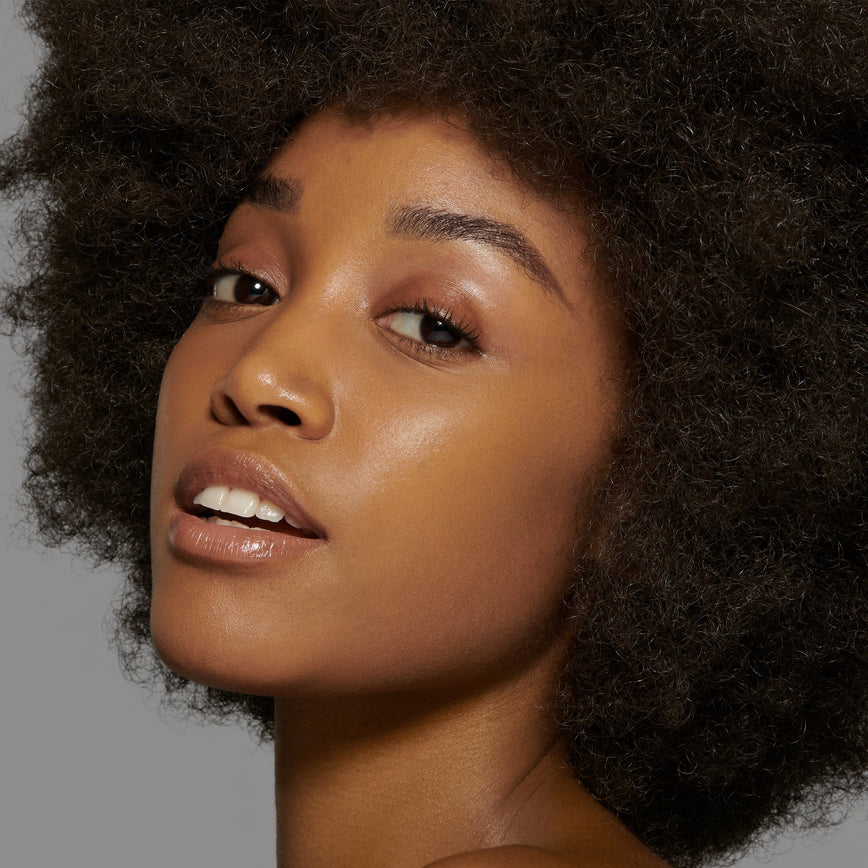 Lisa Eldridge Seamless Skin Foundation Pictured on Model. The model has medium skin and golden olive undertones, brown eyes and curly black hair.