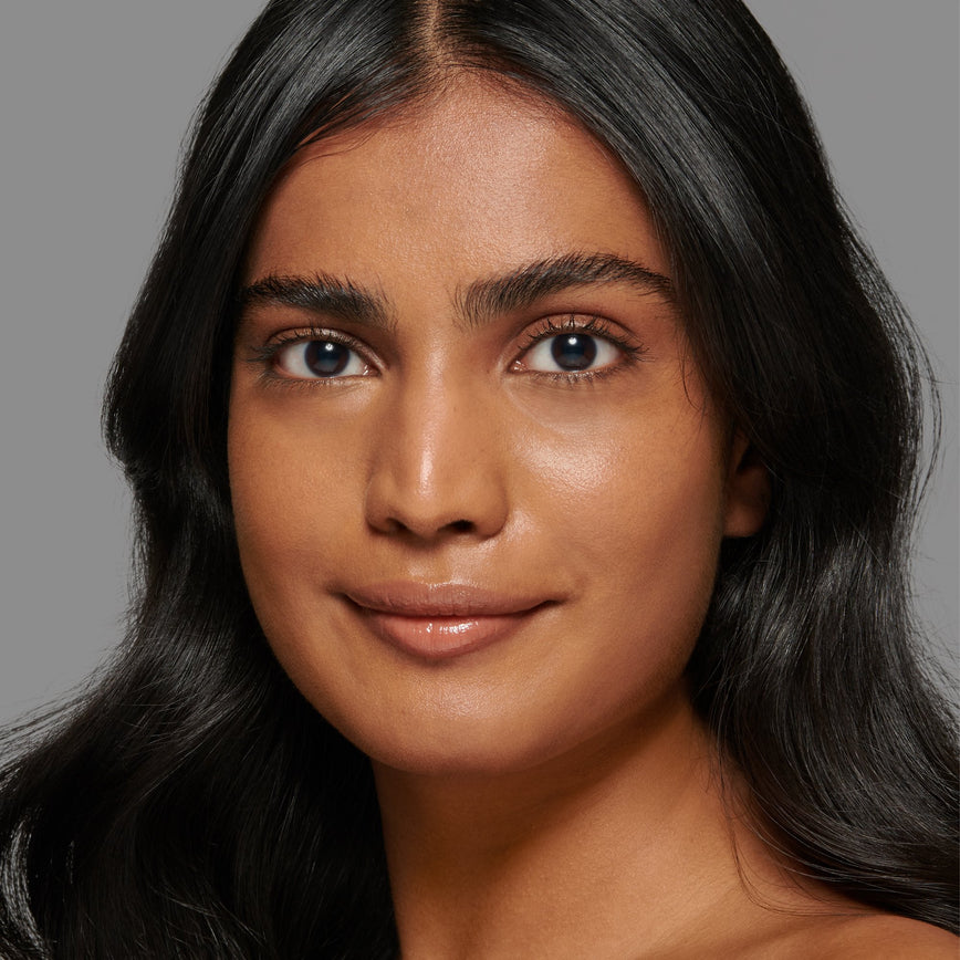 Lisa Eldridge Seamless Skin Foundation Pictured on Model. The model has medium skin and golden terracotta undertones, brown eyes and wavy black hair.