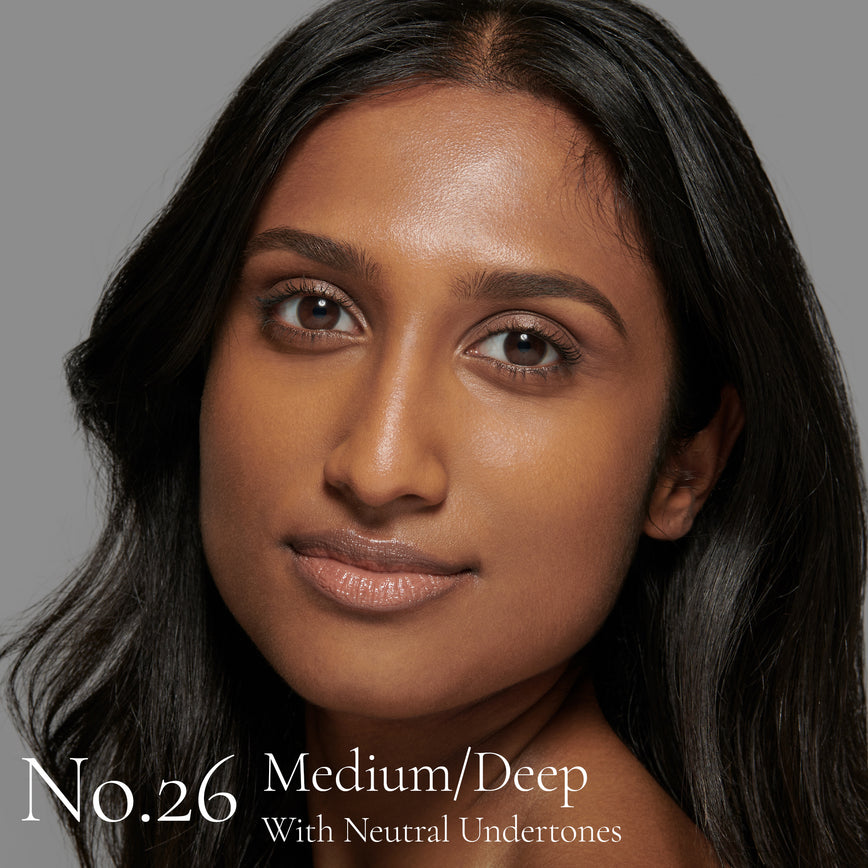 Lisa Eldridge Seamless Skin Foundation Pictured on Model. The model has medium/deep skin and neutral undertones, brown eyes and slightly wavy black hair. The text says ‘No.26 Medium/Deep With Neutral Undertones’