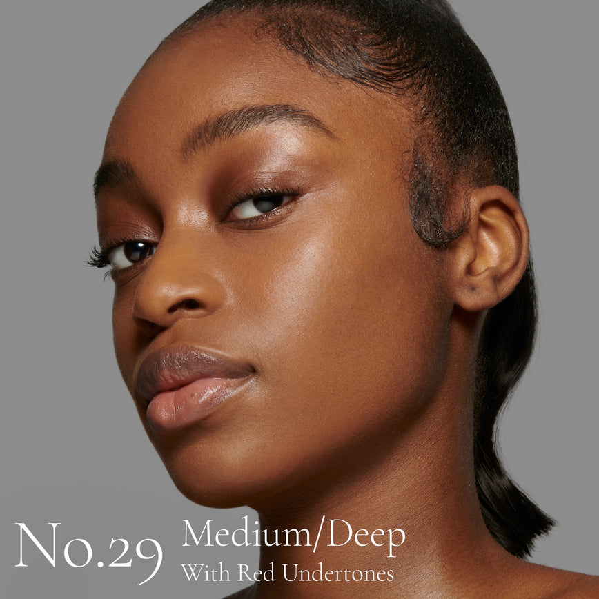 Lisa Eldridge Seamless Skin Foundation Pictured on Model. The model has medium/deep skin and red undertones, brown eyes and black hair. The text says ‘No.29 Medium/Deep With Red Undertones’