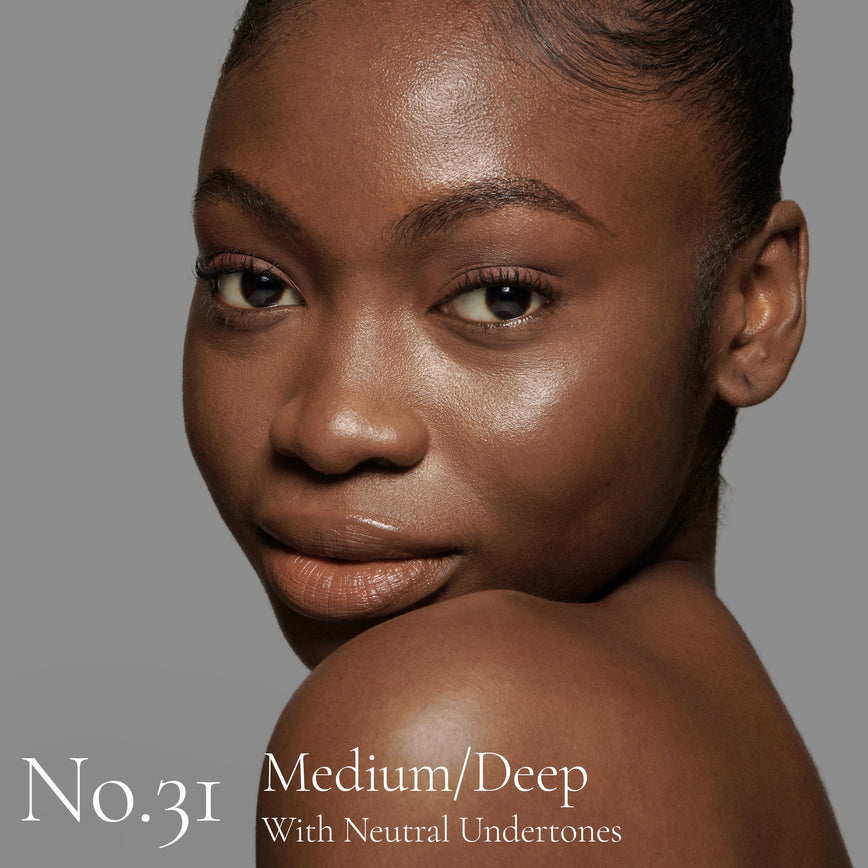 Lisa Eldridge Seamless Skin Foundation pictured on model. The model has medium/deep skin and neutral undertones, brown eyes and black hair. The text says ‘No.31 Medium/Deep With Neutral Undertones’