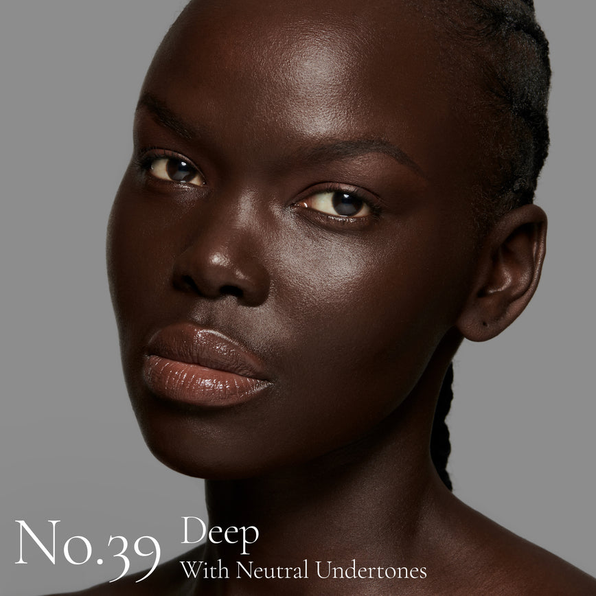 Lisa Eldridge Seamless Skin Foundation pictured on model. The model has deep skin and neutral undertones, brown eyes and black hair. The text says ‘No.39 Deep With Neutral Undertones’