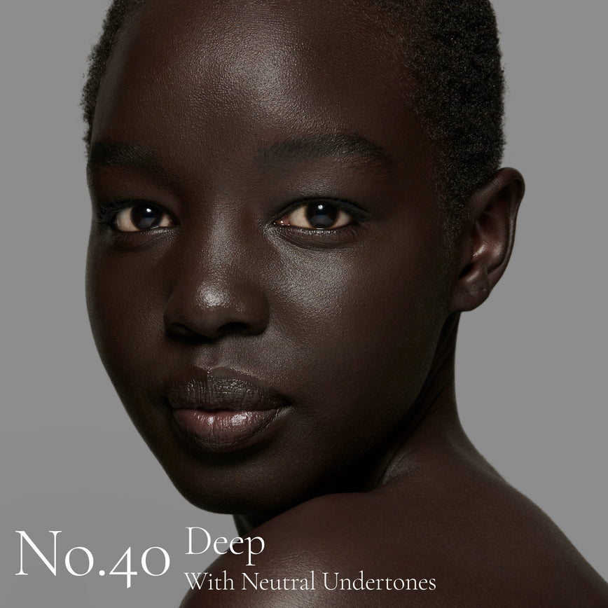Lisa Eldridge Seamless Skin Foundation pictured on model. The model has deep skin and neutral undertones, brown eyes and black hair. The text says ‘No.40 Deep With Neutral Undertones’