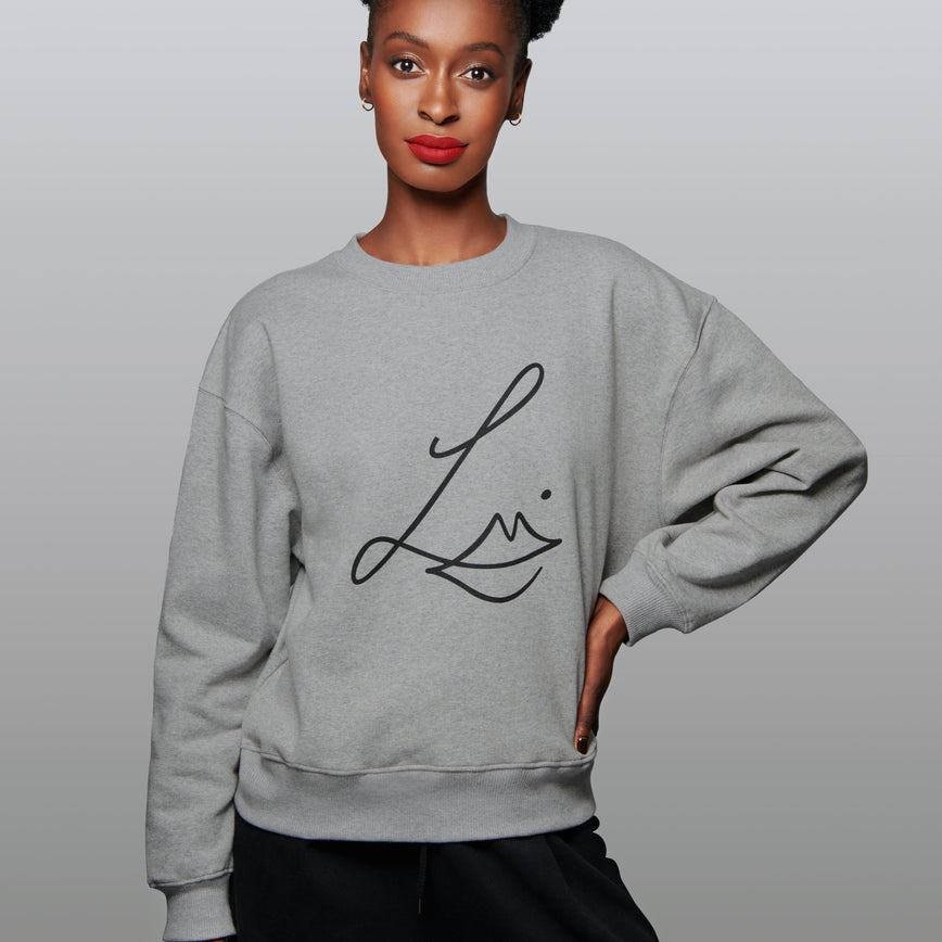 Lisa Eldridge Studio Sweatshirt in grey on a slim model. The sweatshirt has dropped shoulders and the Lisa Eldridge logo large on the front.