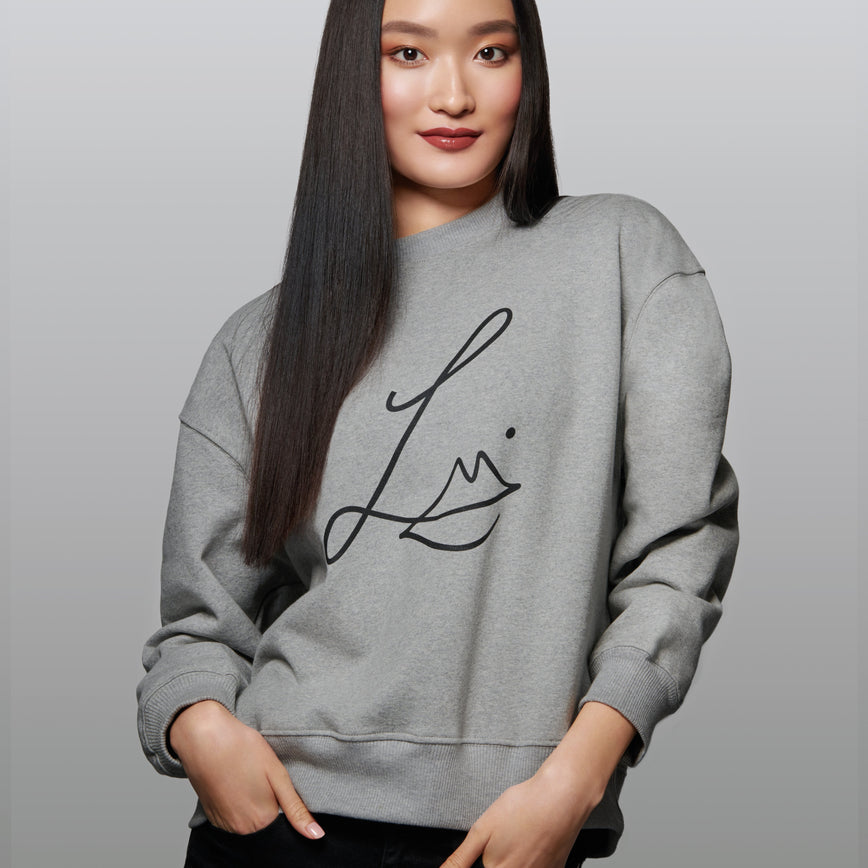 Lisa Eldridge Studio Sweatshirt in grey on a slim model. The sweatshirt has dropped shoulders and the Lisa Eldridge logo large on the front.