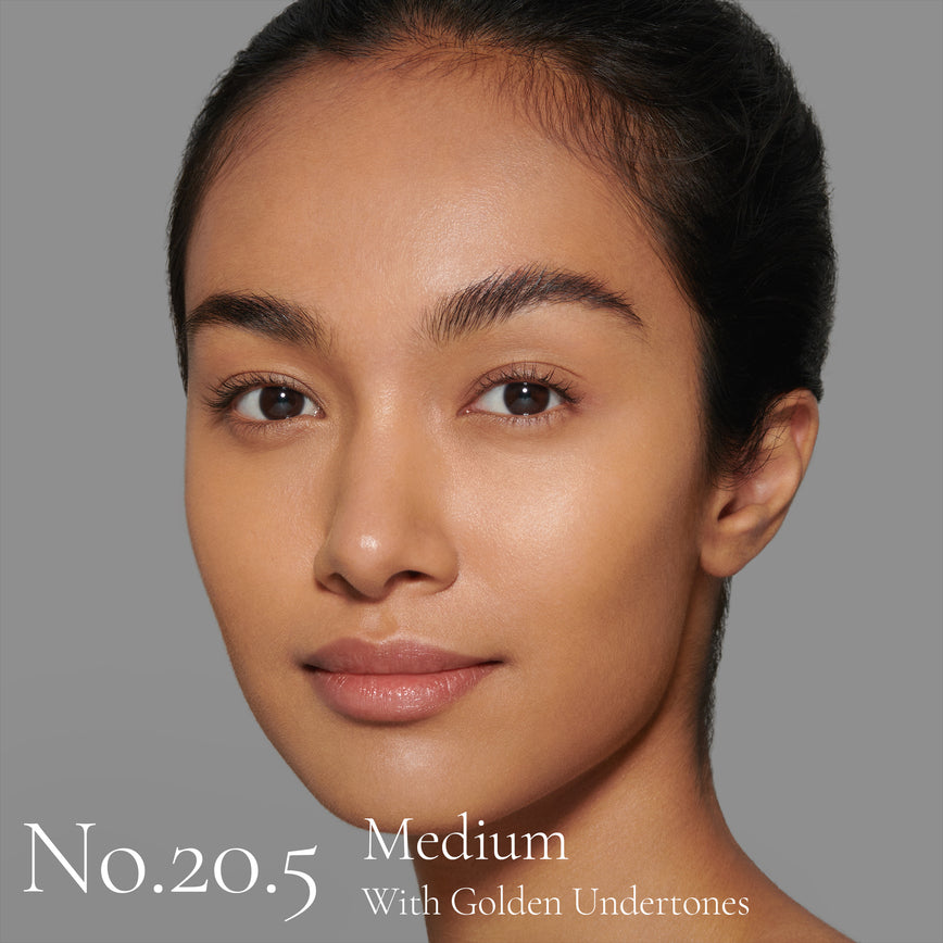 Lisa Eldridge Seamless Skin Foundation pictured on model. The model has medium skin and golden undertones, brown eyes and black hair. The text says ‘No.20.5 Medium With Golden Undertones’